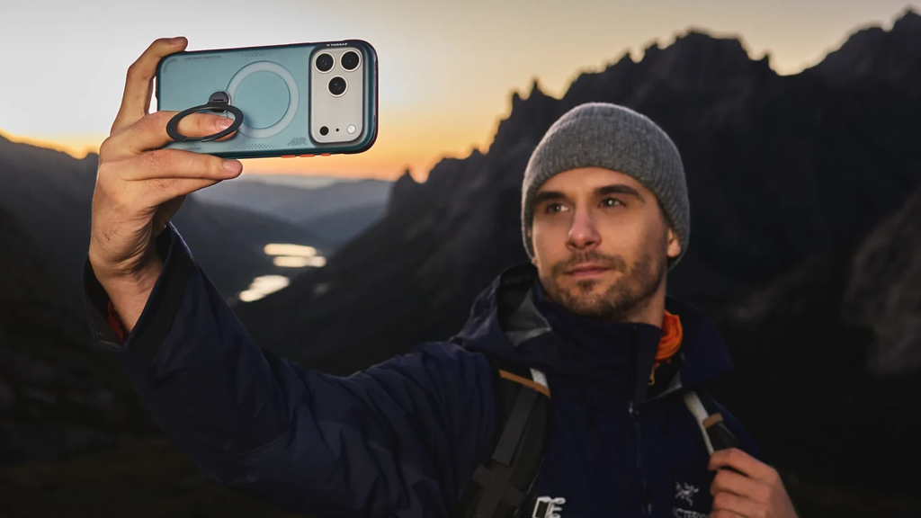 Mann fotografiert bei Sonnenaufgang im Gebirge mit dem iPhone in türkisfarbener Hülle