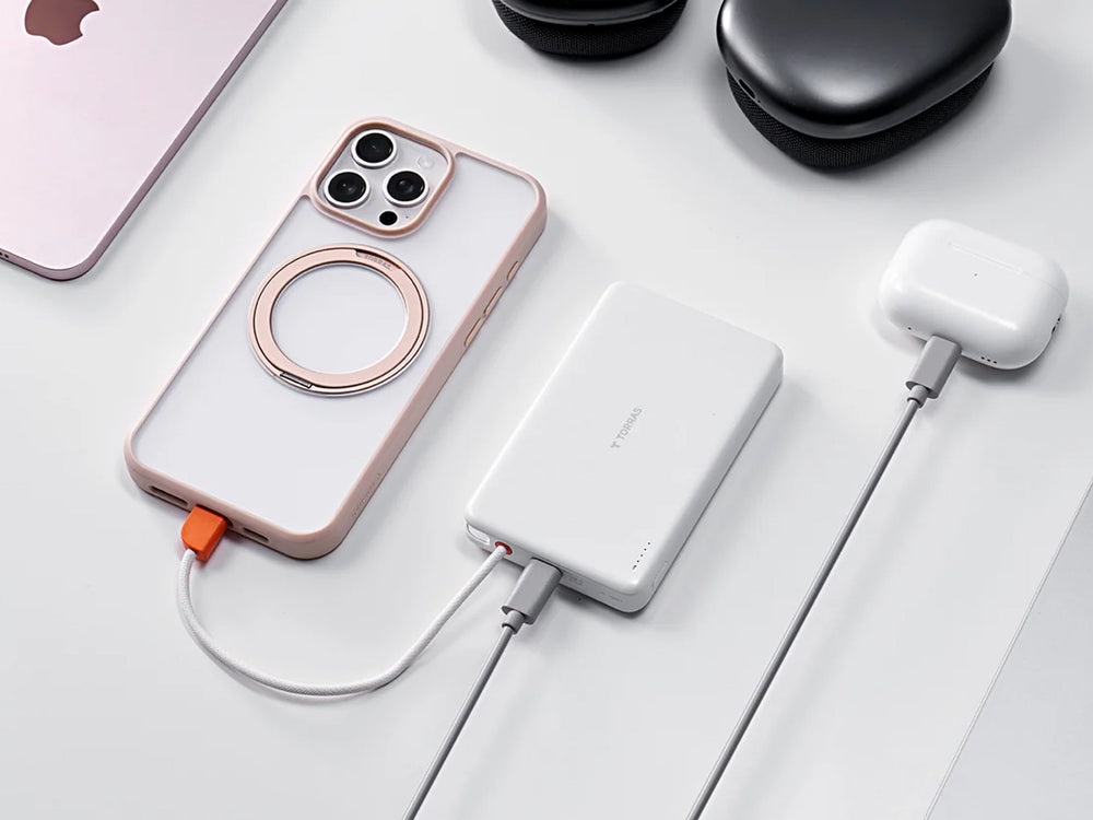 iPhone 18 Pro mit MagSafe-Ring neben Powerbank und Kopfhörern auf weißem Tisch